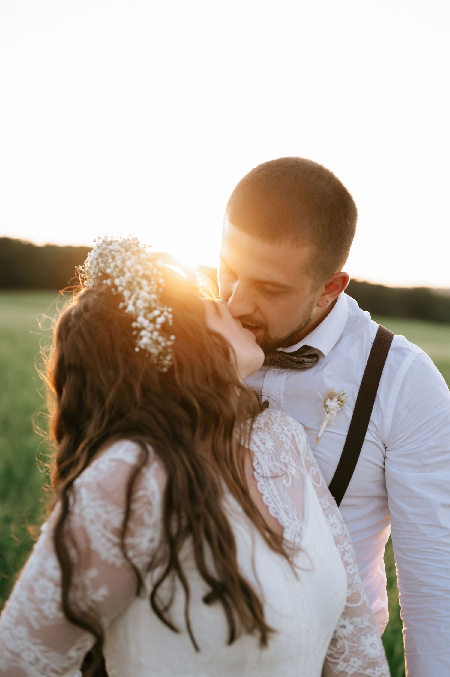 Romantic sunset wedding portraits in a field with warm golden light.