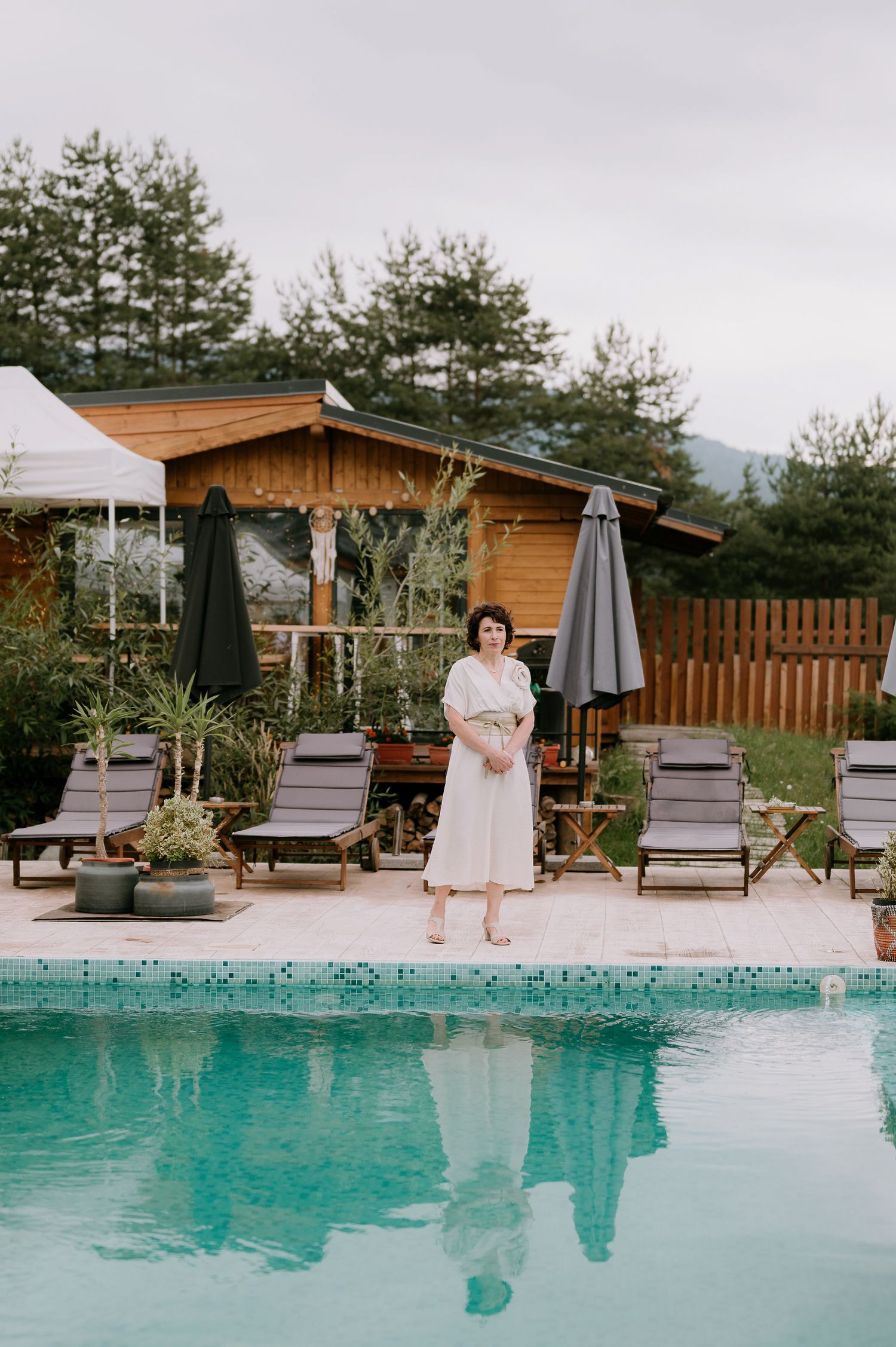 Outdoor poolside setup with lounge chairs and wooden cabana decorated for a special event.