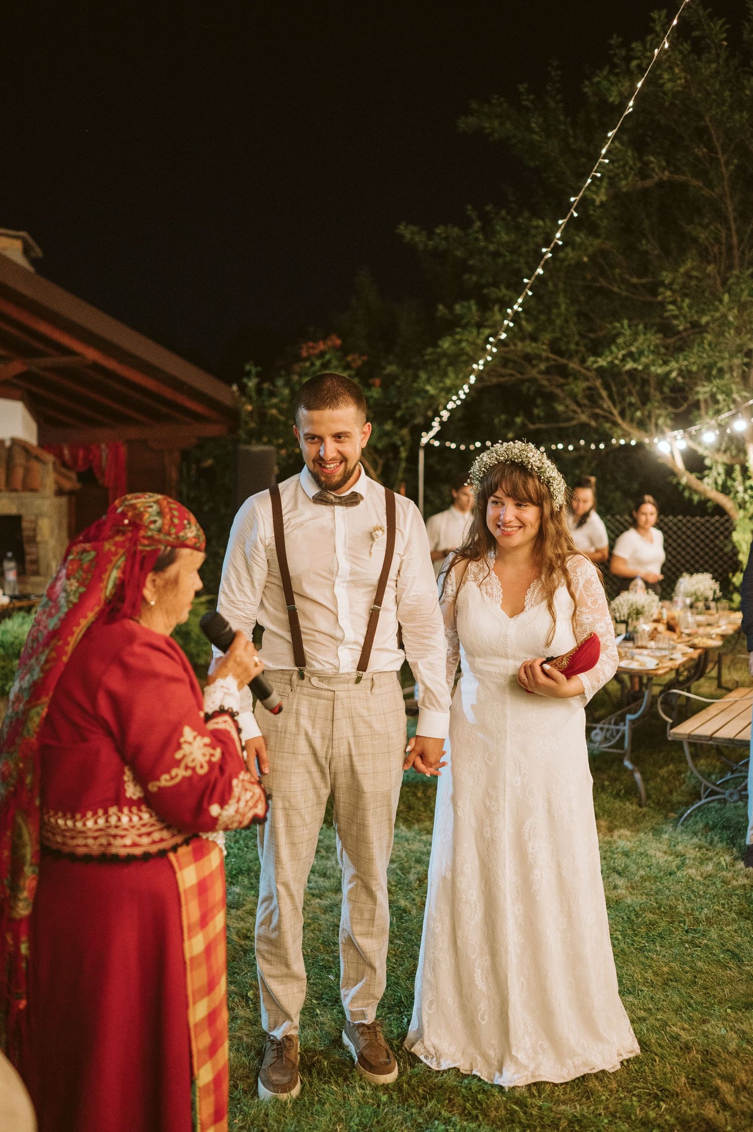 Outdoor wedding celebration with string lights and traditional folk elements.