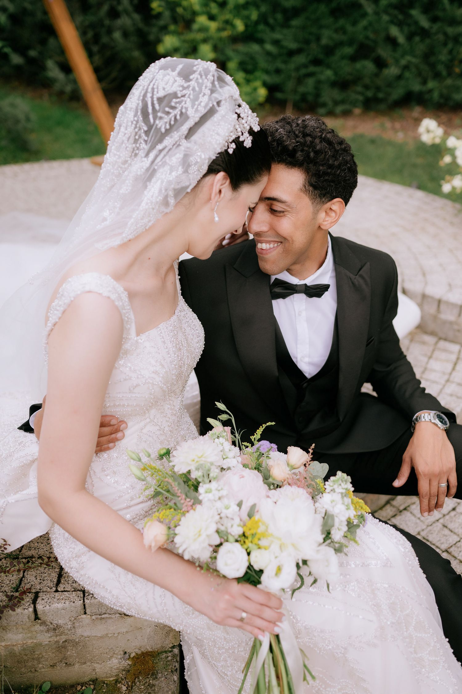 Intimate wedding portrait on stone path with white floral bouquet.
