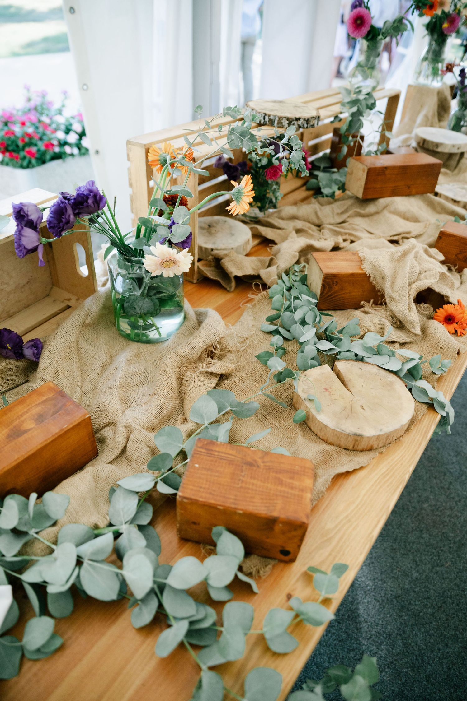 Rustic wooden decor elements with eucalyptus and floral arrangements on display table.