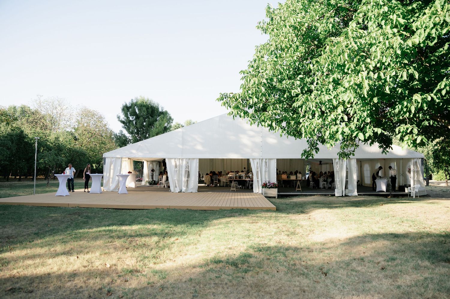 Panoramic view of white wedding tents set up in a scenic outdoor location.
