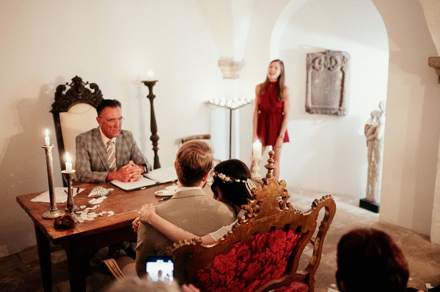 Intimate indoor ceremony setting with candlelight and vintage furniture.