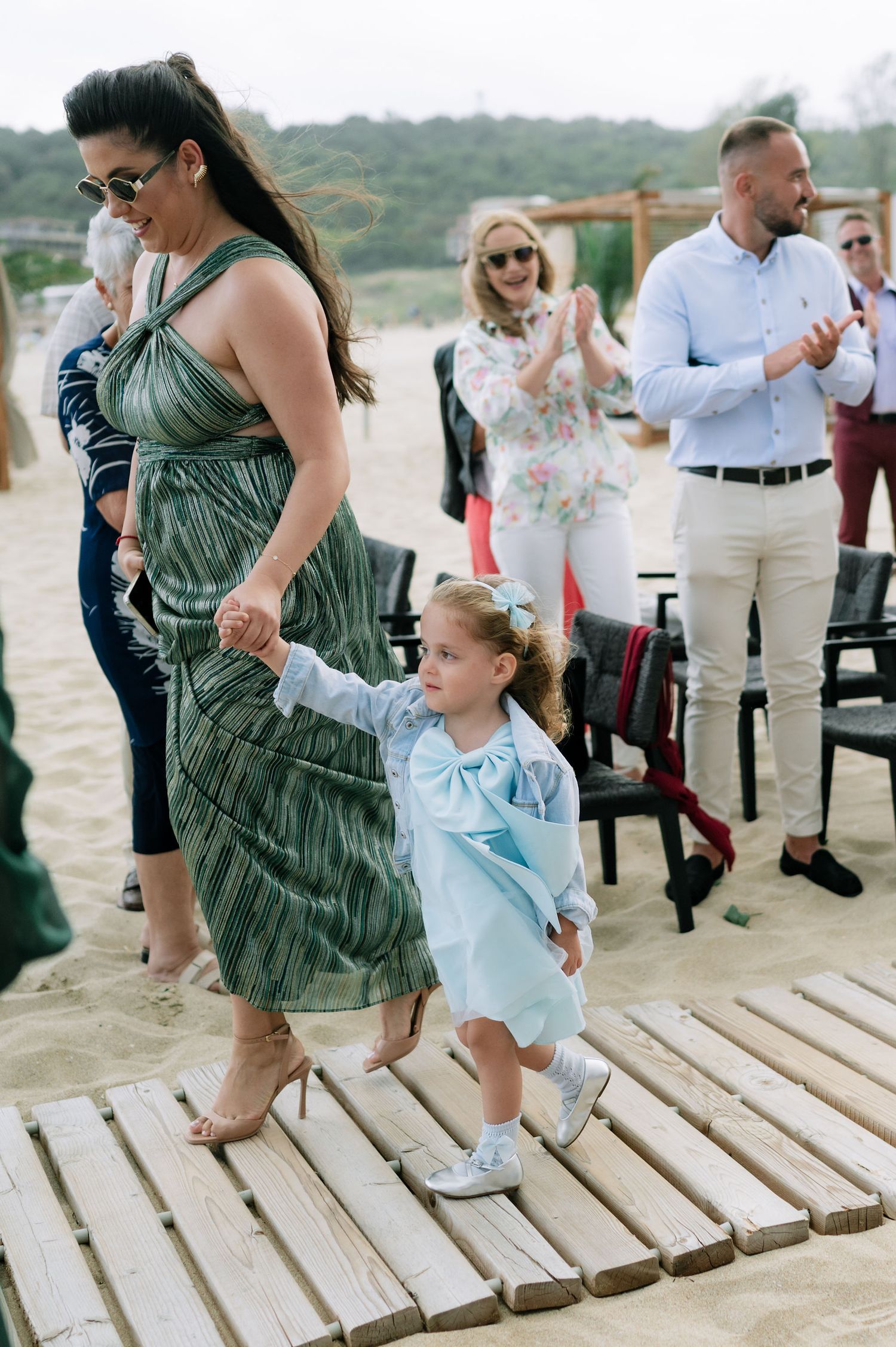 People walking on wooden boardwalk during beach wedding celebration.
