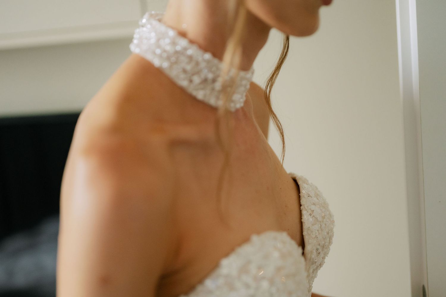 Detail shot of an ornate lace neckline on a white wedding gown.