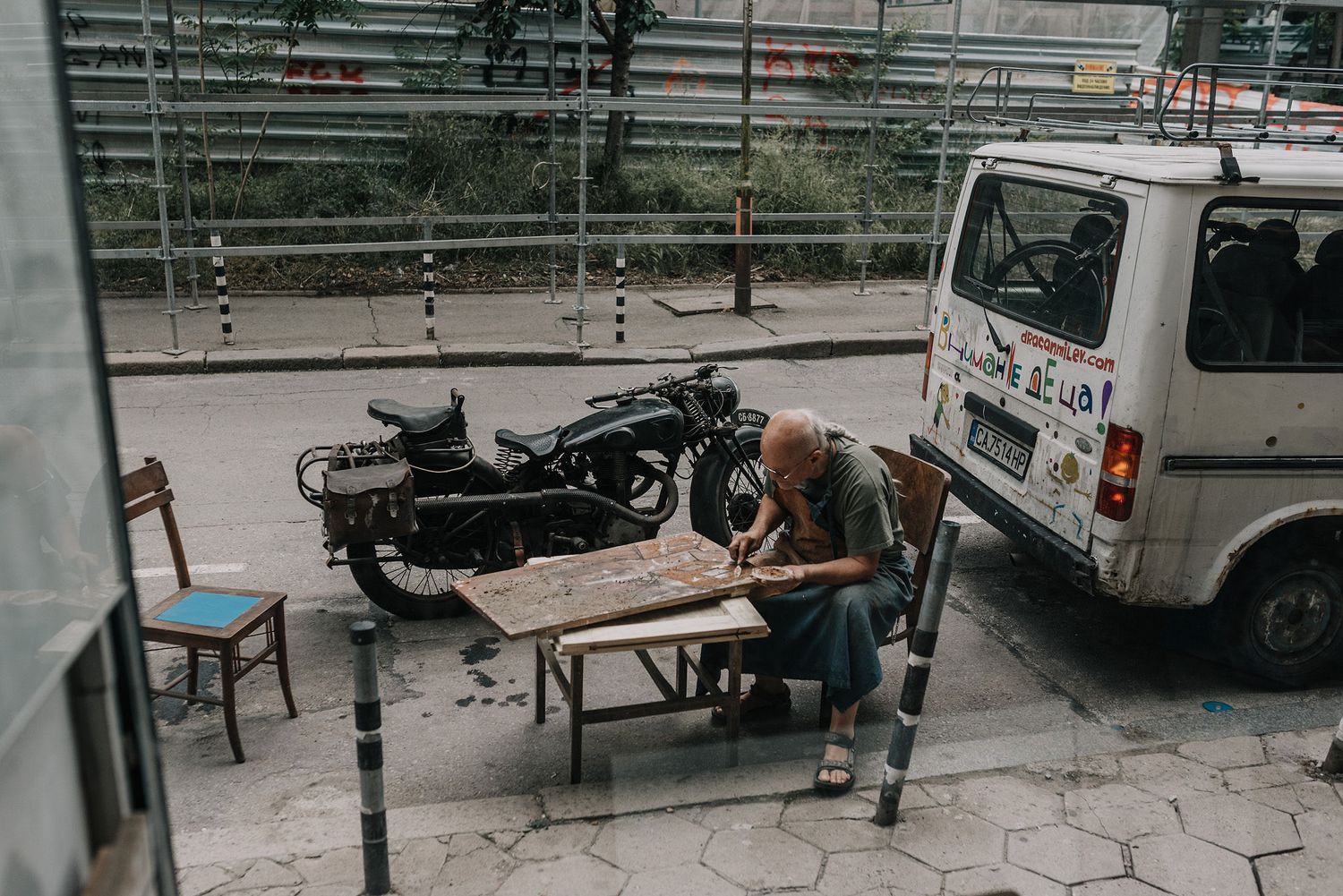 Urban scene with benches and motorcycles parked along a walkway.