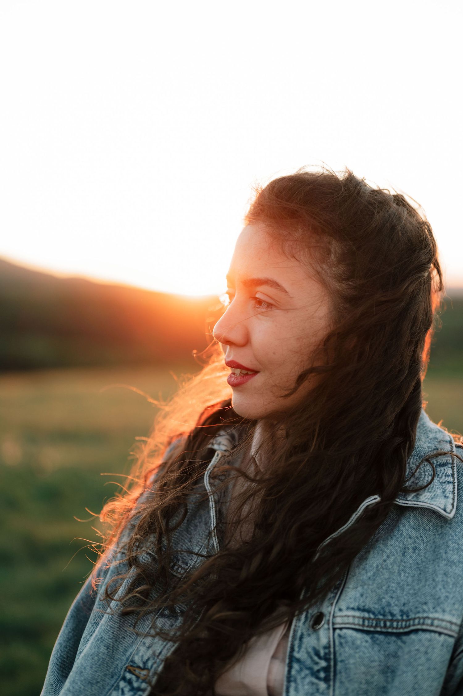 A candid series of outdoor portraits at sunset with a denim jacket and flowing dark hair.