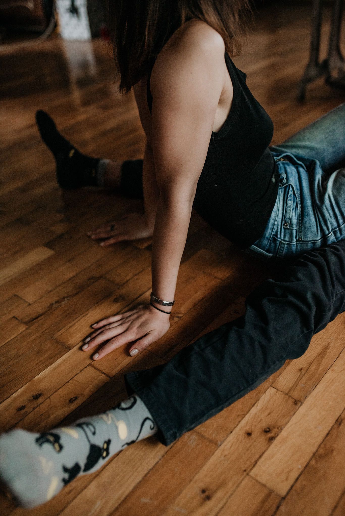 Close-up view of a person sitting on wooden flooring wearing a dark dress and white socks.