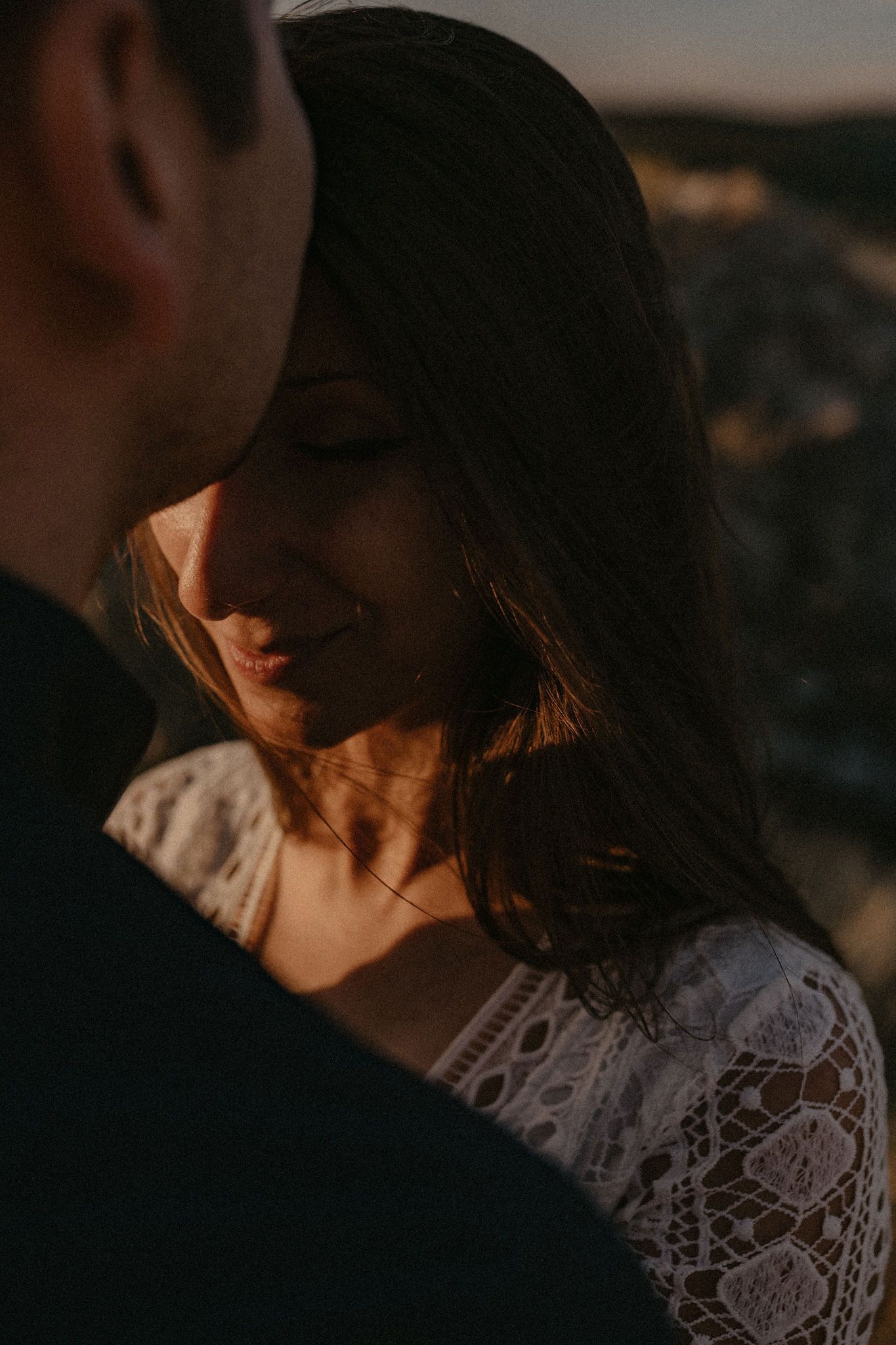 A couple shares an intimate moment at sunset wearing formal attire.