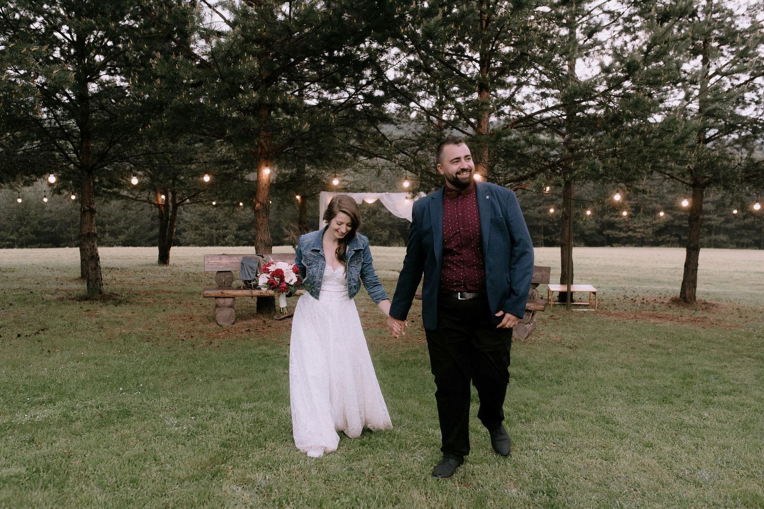 Wedding celebration in a rustic outdoor setting surrounded by tall pine trees.