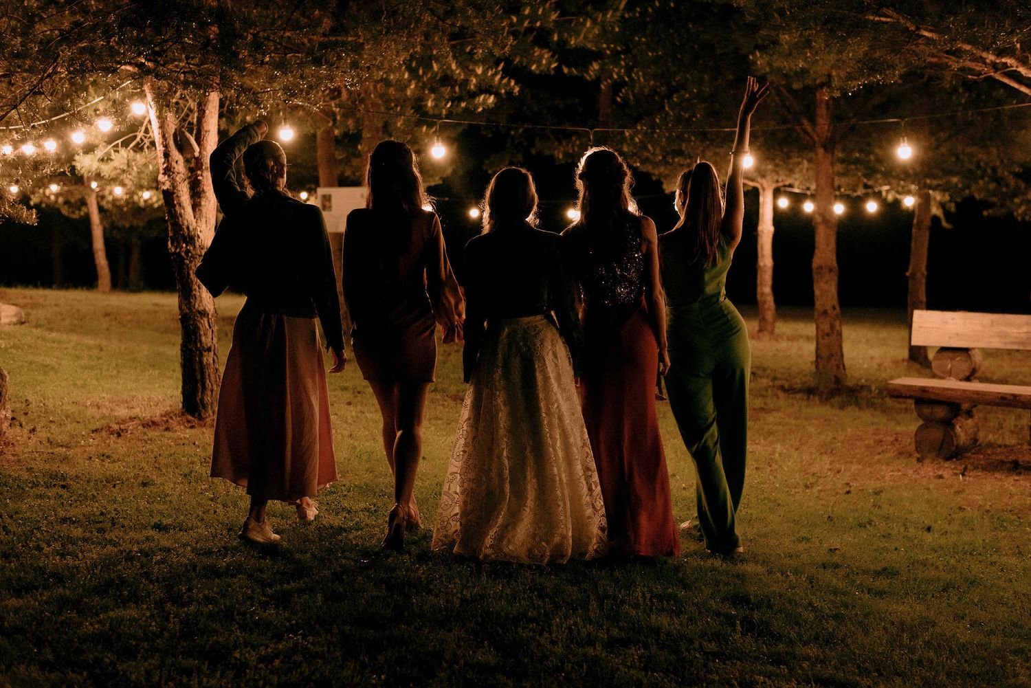 Wedding guests gather outdoors at night under strung lights creating a romantic atmosphere.