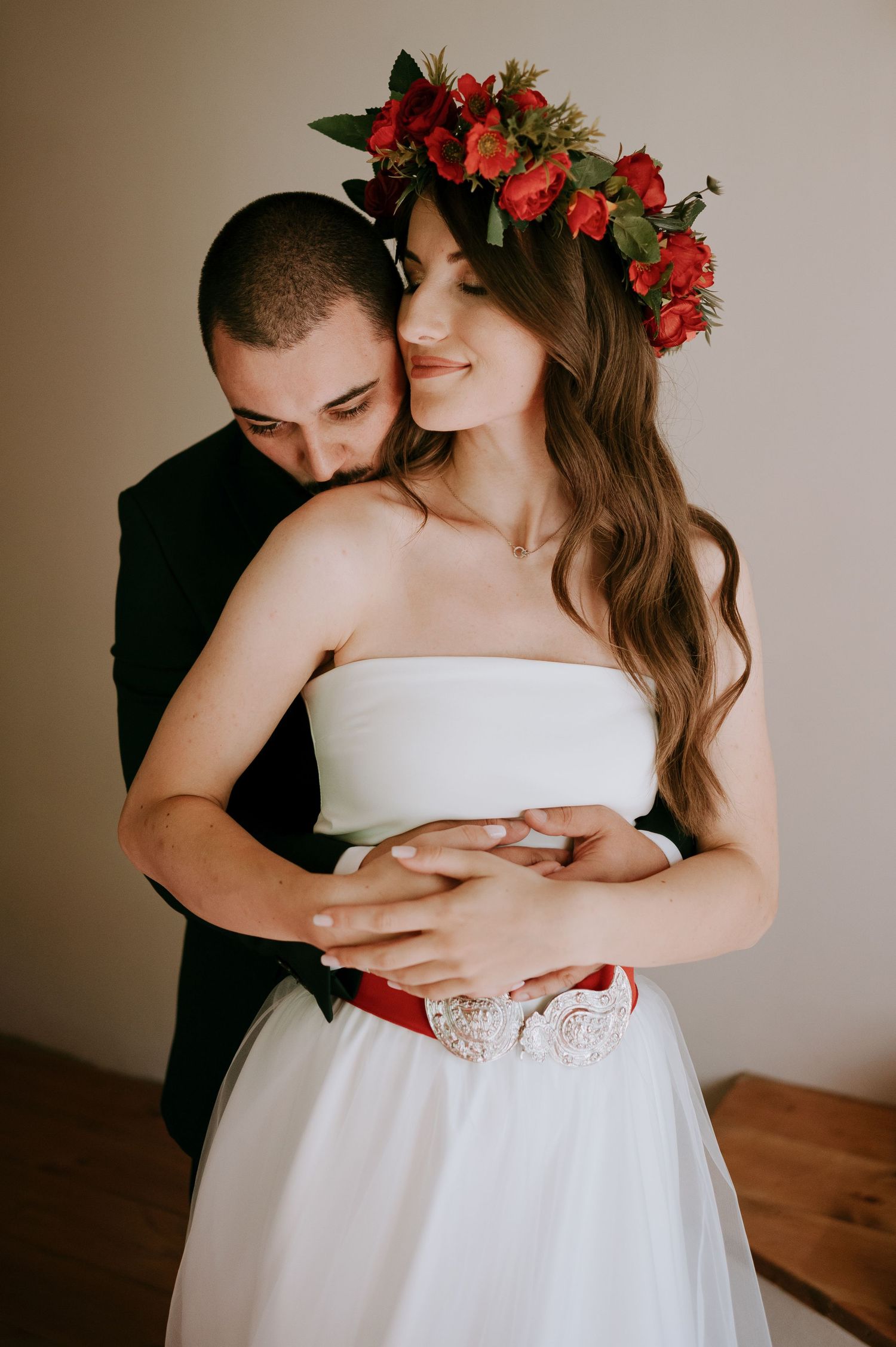 A romantic embrace between newlyweds with the bride wearing a floral crown and white dress.