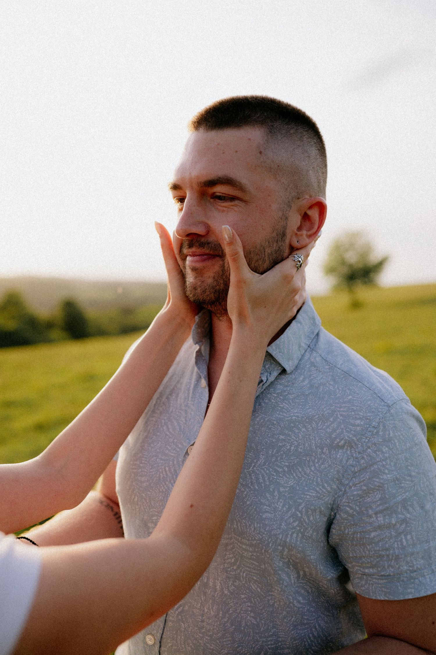 Playful interaction between couple during outdoor photoshoot in golden sunlight.
