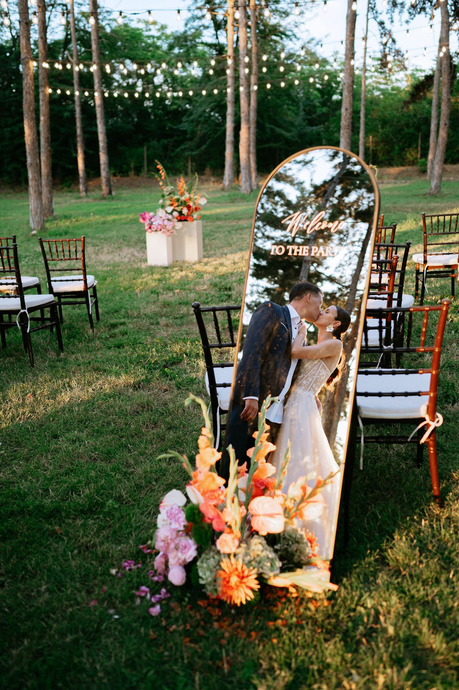 Enchanted forest wedding setup with twinkling lights and floral decorations among pine trees.