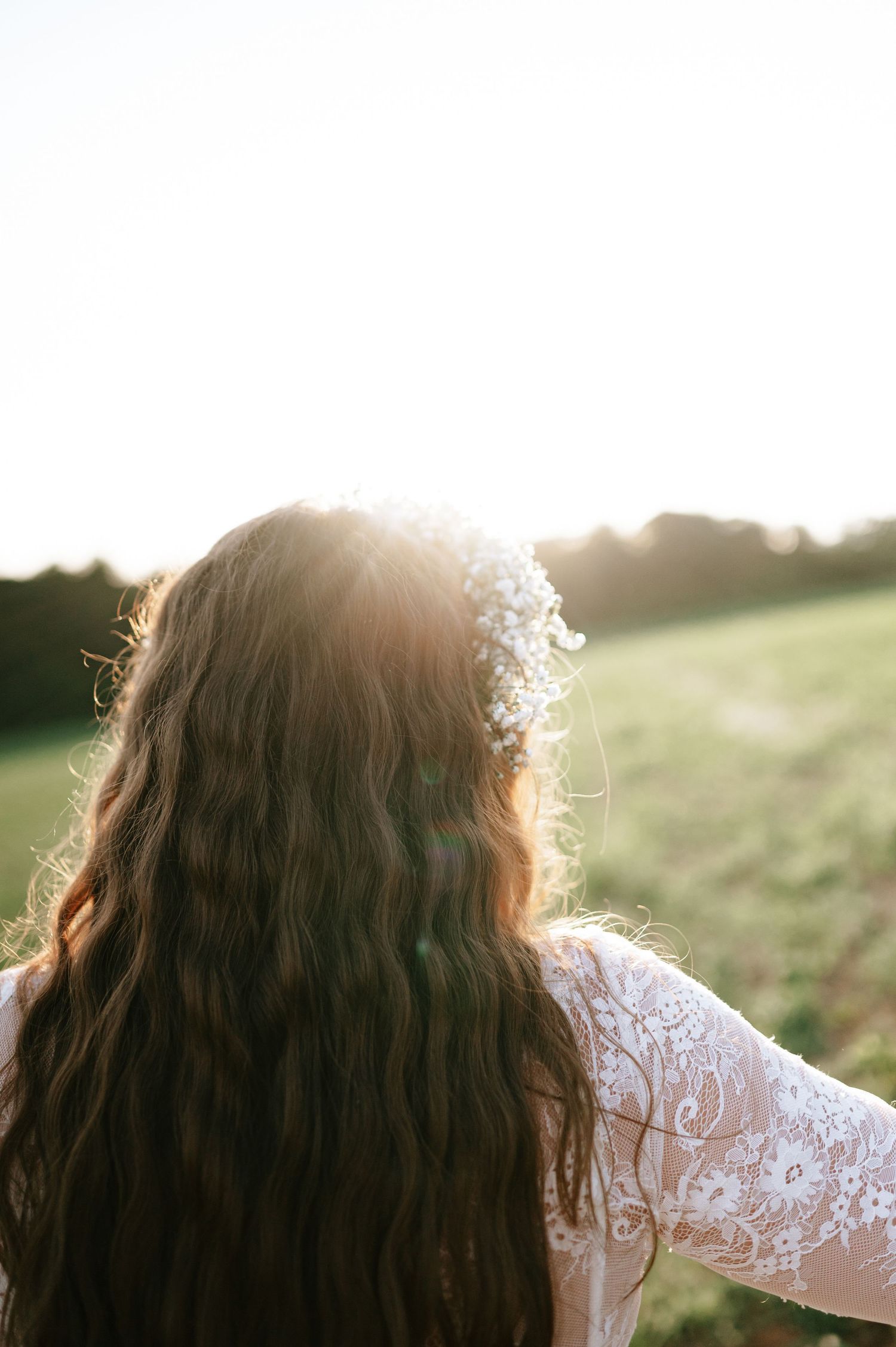 Close-up of bride's hair and floral crown backlit by golden sunset.