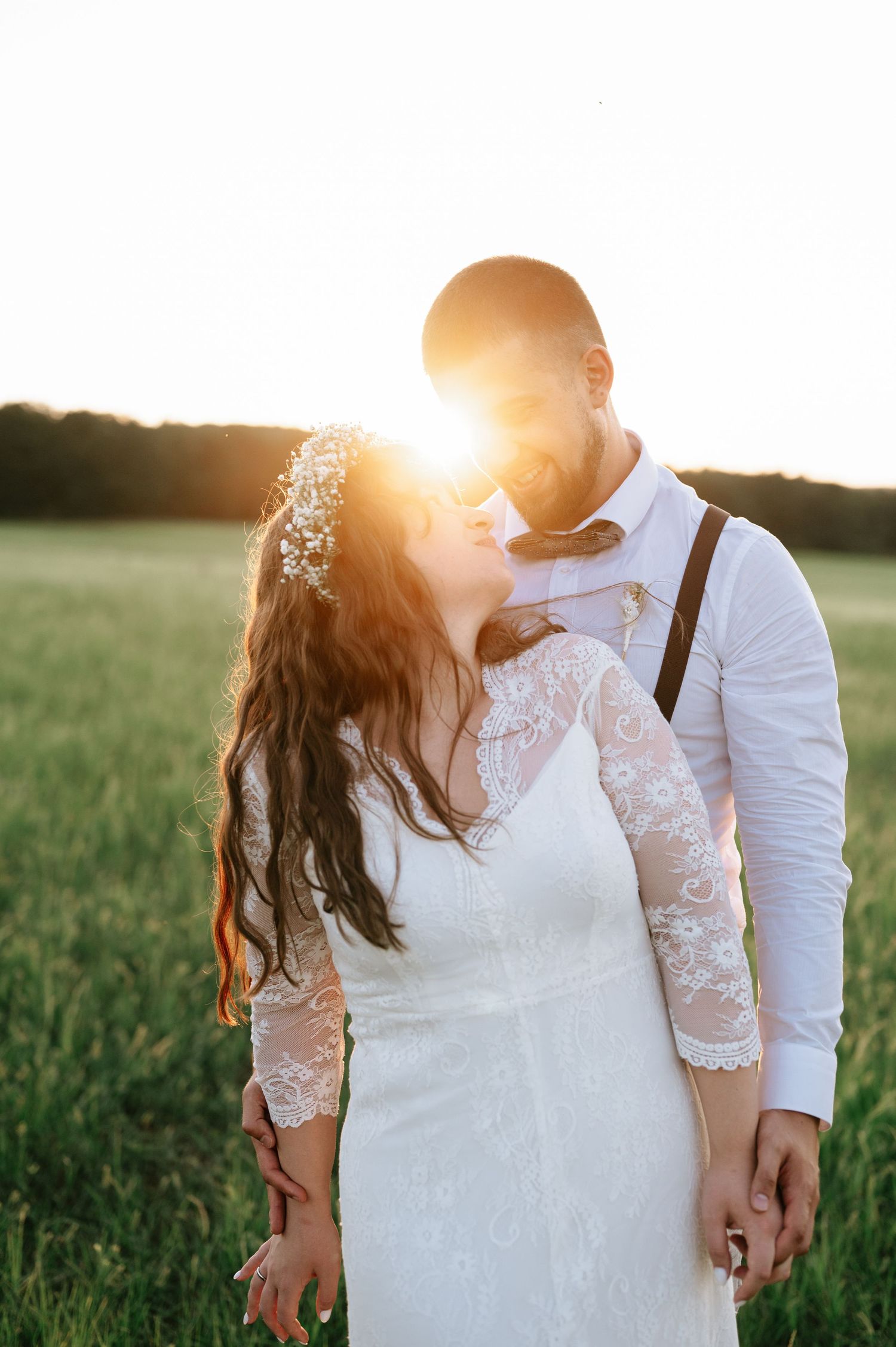 Romantic sunset portrait of newlyweds in an open field.