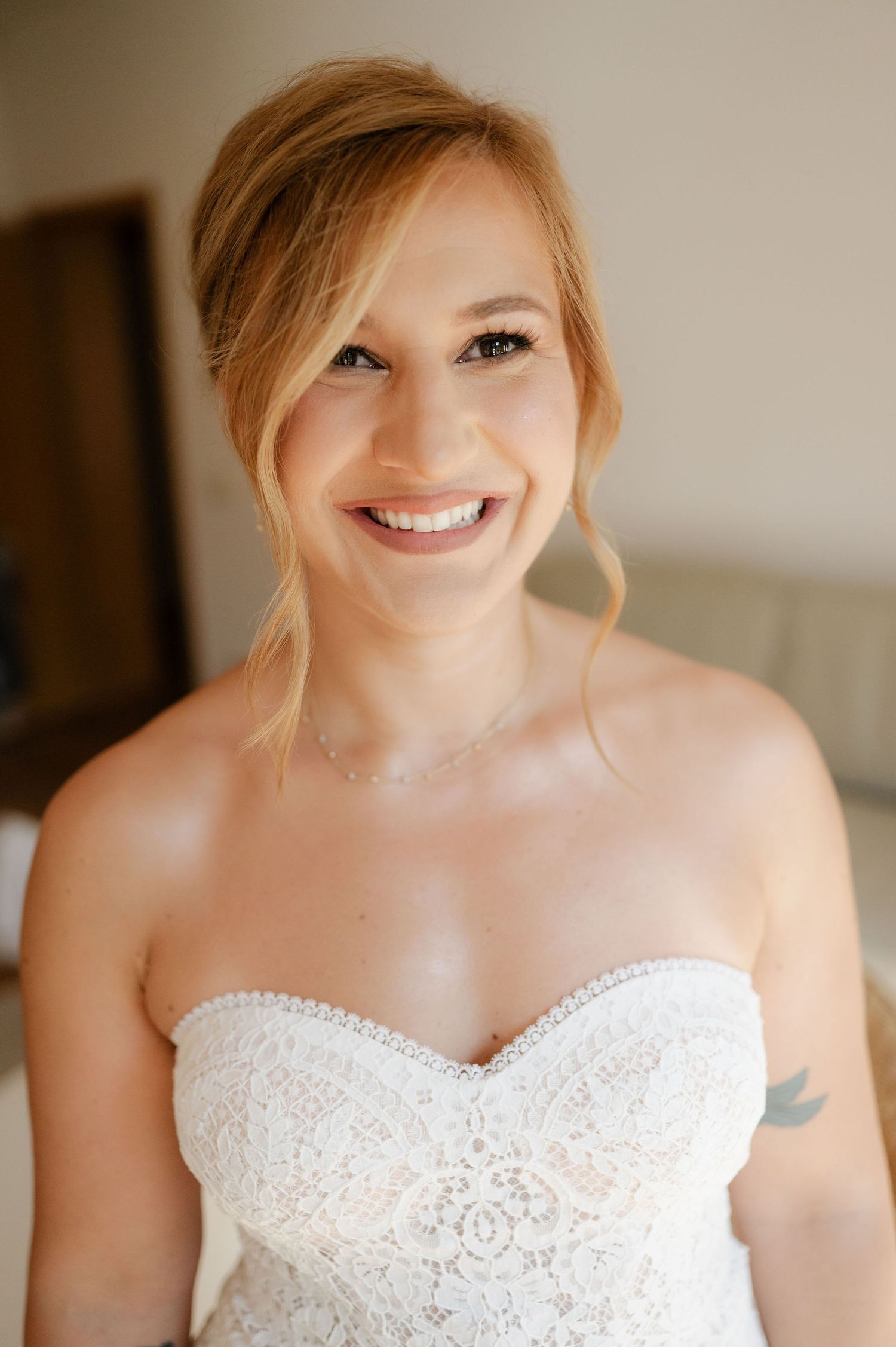 Radiant bride wearing a strapless lace wedding gown with natural makeup.