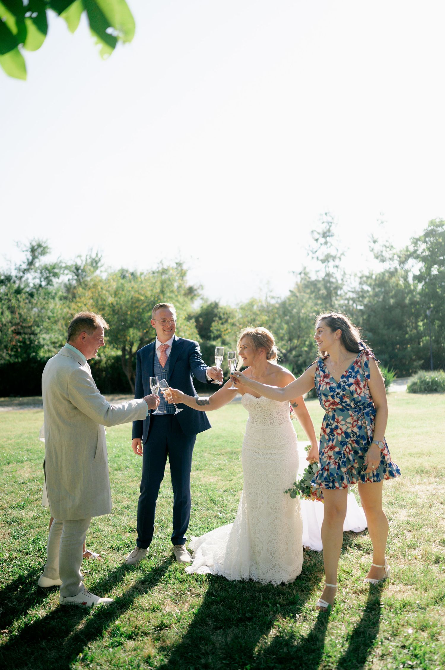 Wedding party members share laughter and celebrations in a sun-drenched outdoor setting.