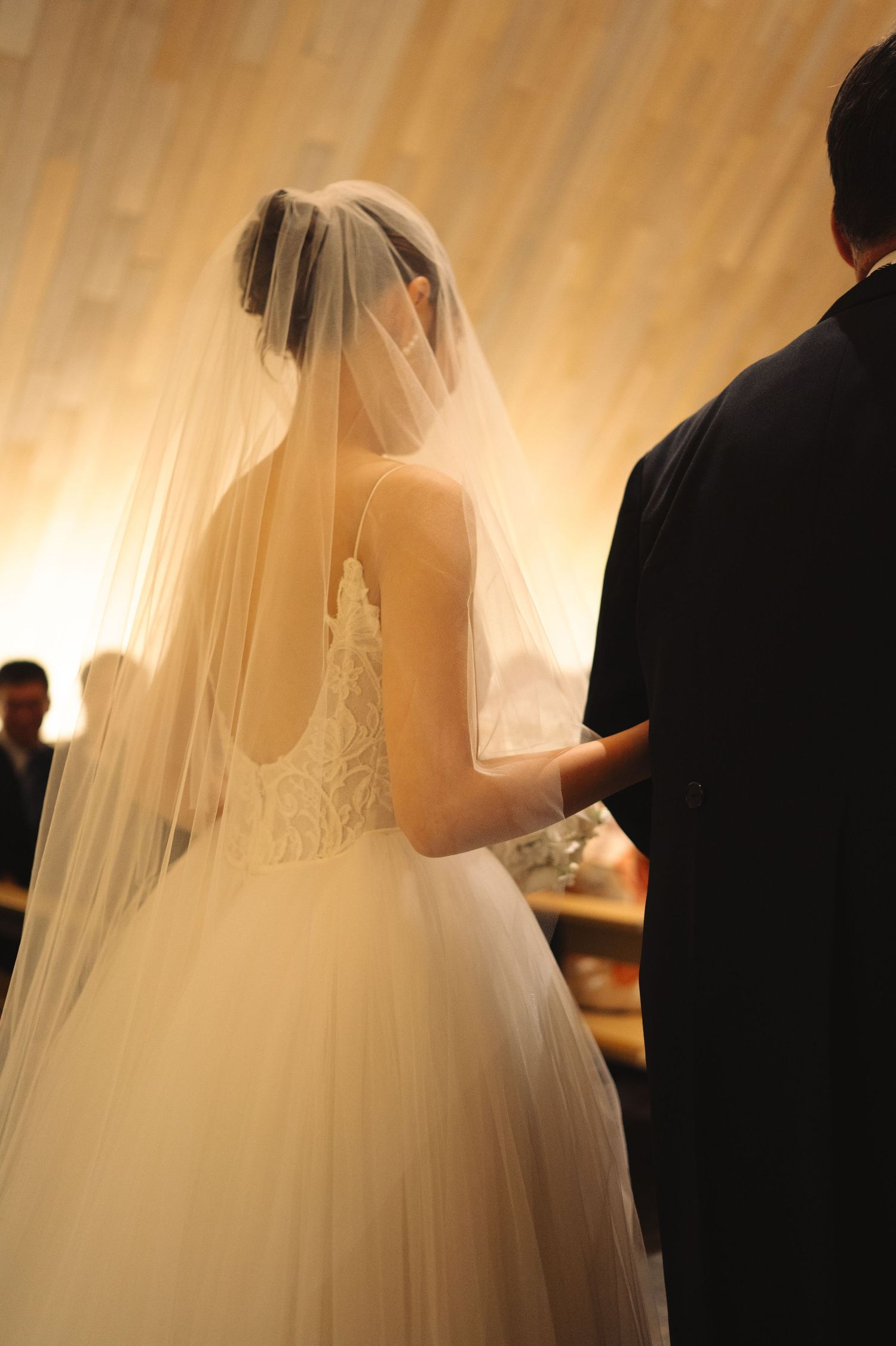 Bride in flowing white dress and veil during wedding ceremony.