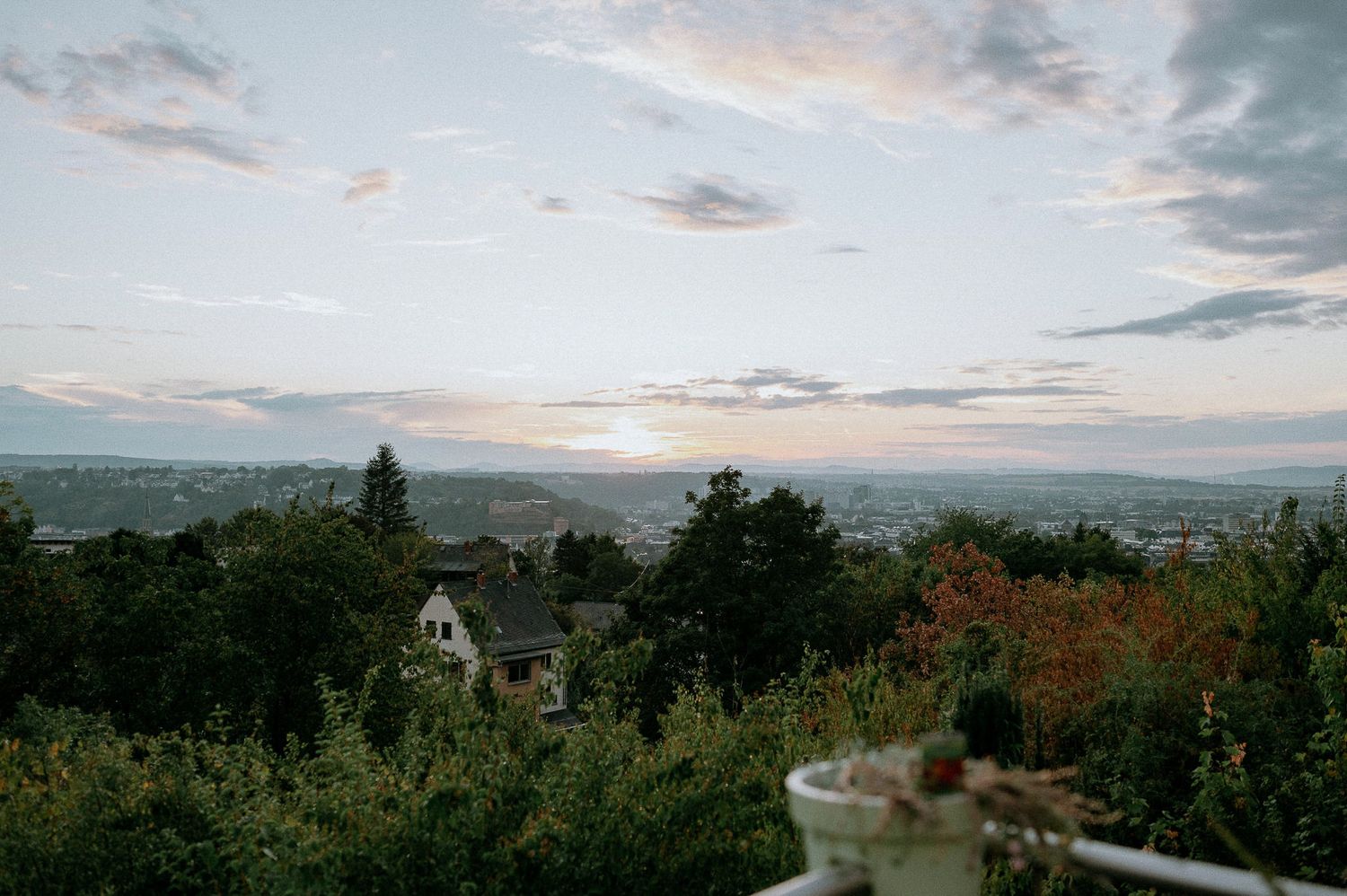 Scenic sunset view over a hillside town with mountains in the distance.