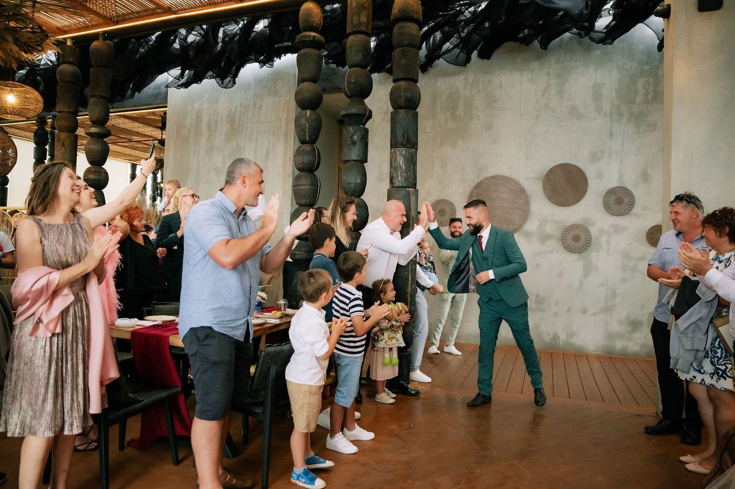 Wedding celebration with guests applauding in a rustic venue with decorative columns.