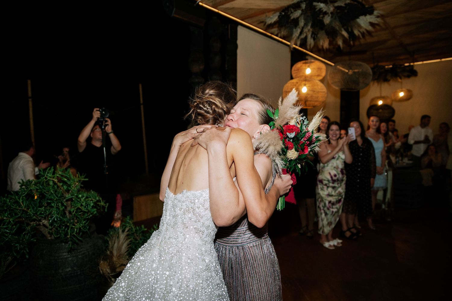 Lively dance floor scene at a wedding reception with guests dancing under pendant lights.