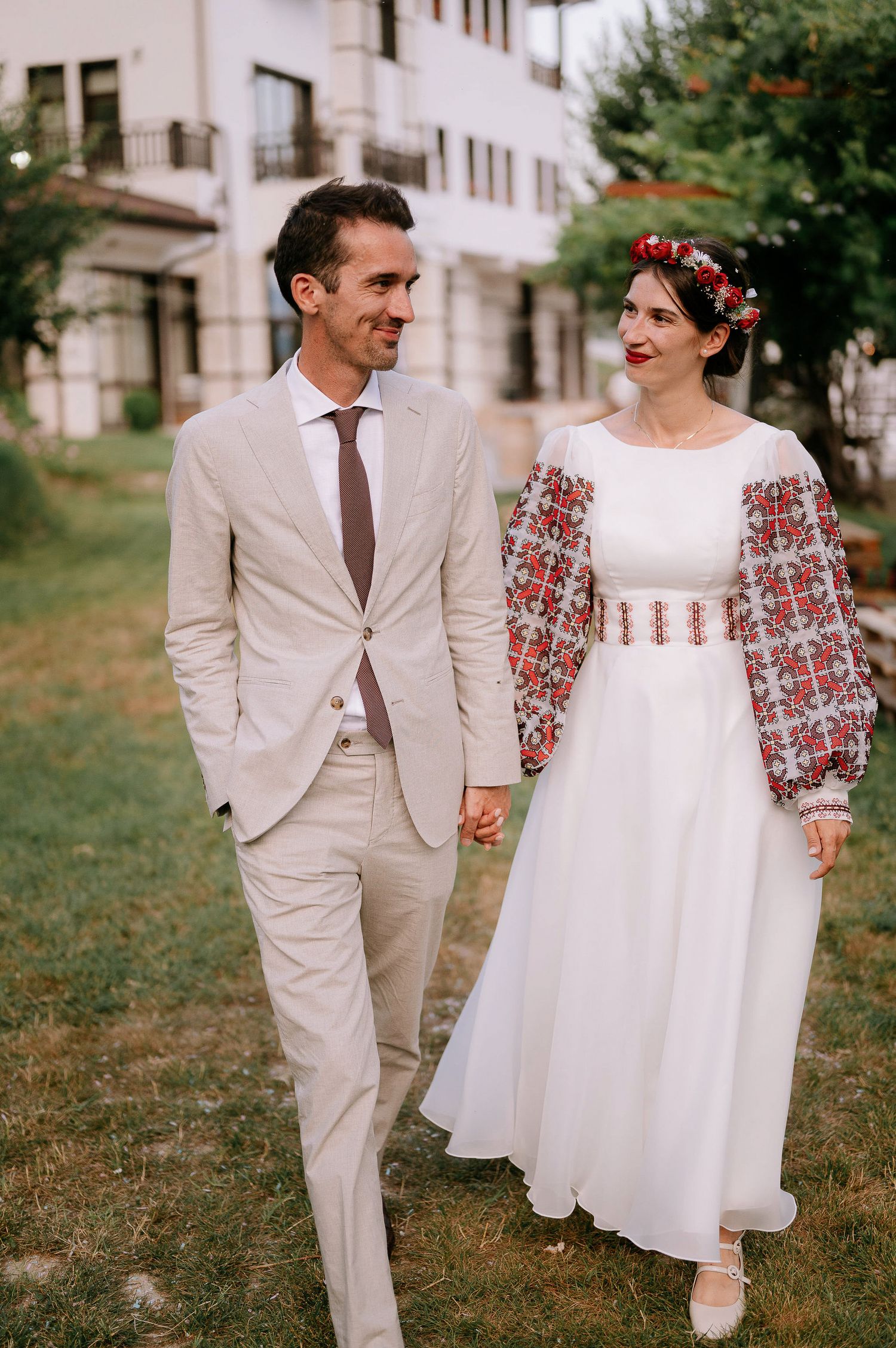 A romantic wedding photo showing a couple in vintage-inspired attire with embroidered details.