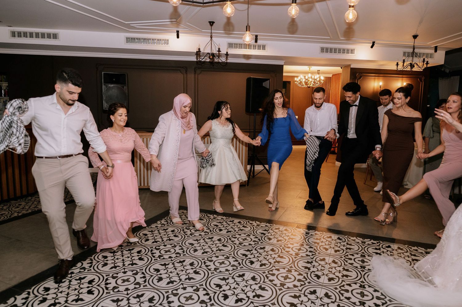 Wedding guests dance in formation on a black and white patterned floor.