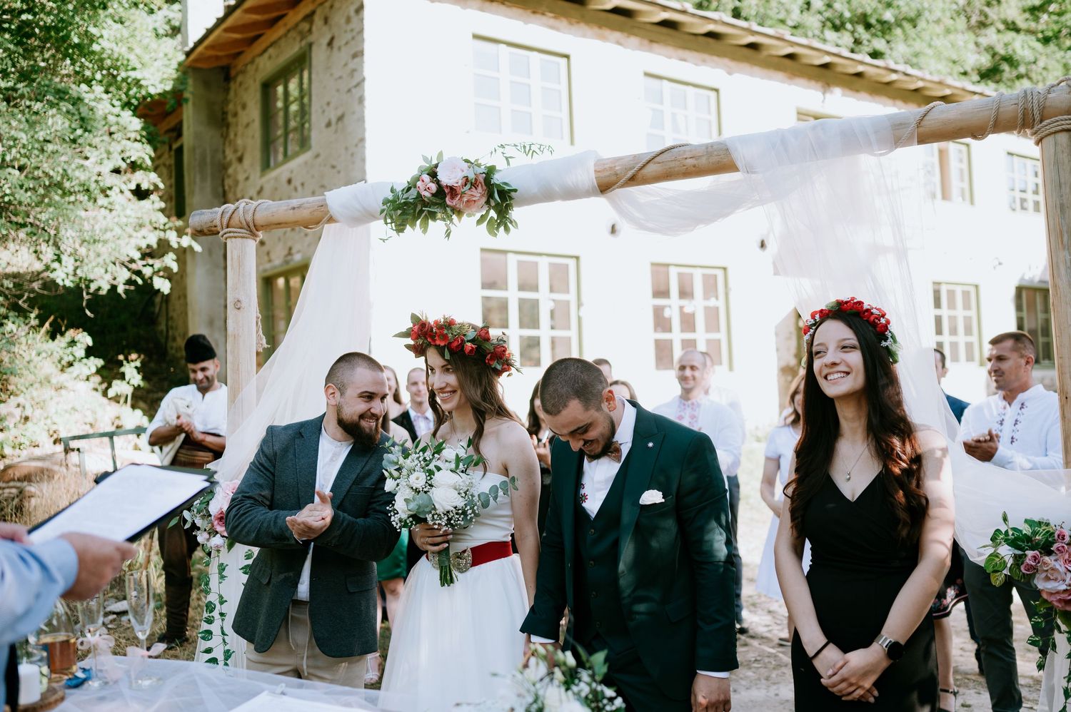 Outdoor wedding celebration with guests mingling near stone building facade.