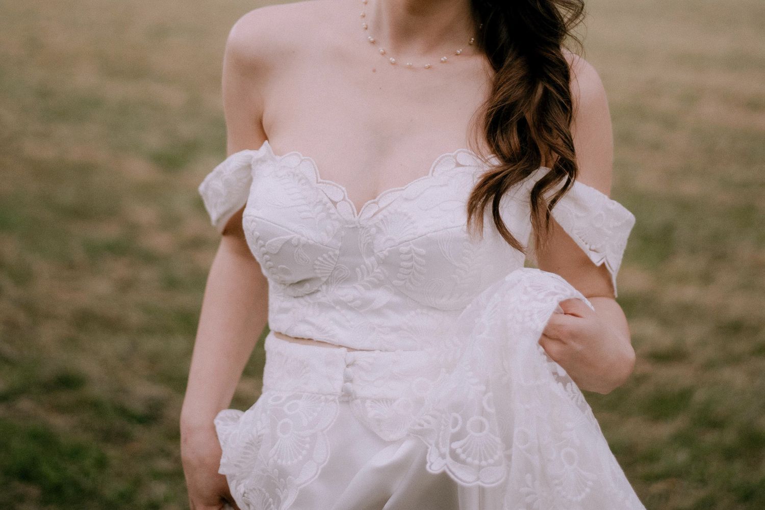 A white lace wedding dress detail shot showing delicate fabric and floral embellishments.