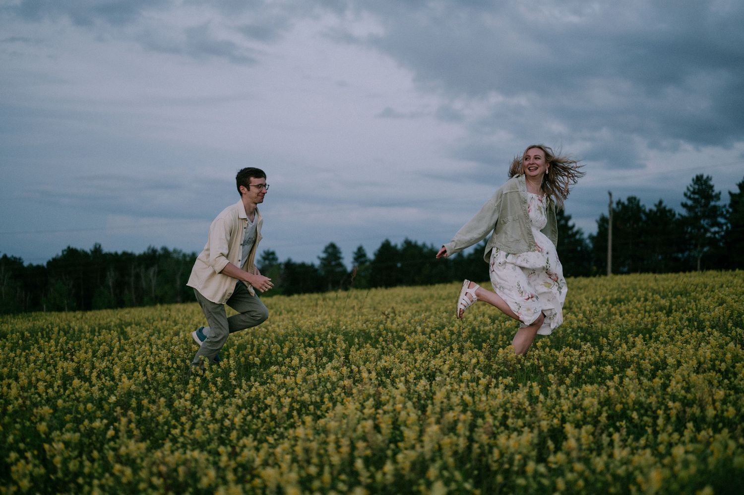 Two people share tender moments while standing in a vast field of yellow flowers.