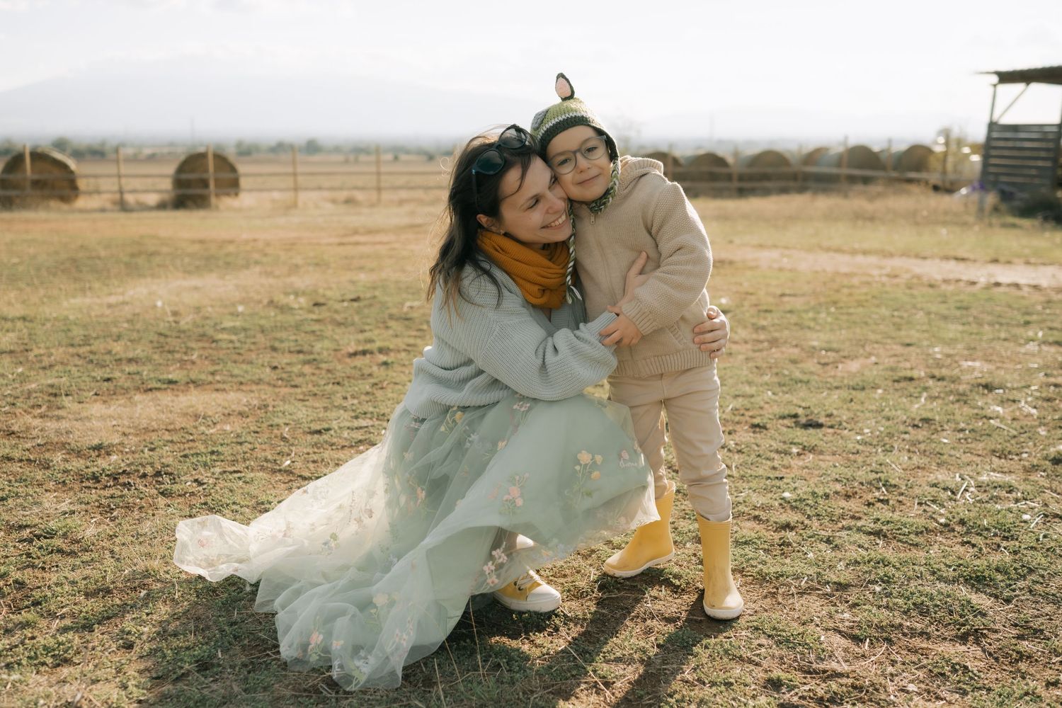 A couple in wedding attire poses playfully together in a sunny field during their outdoor photo session.