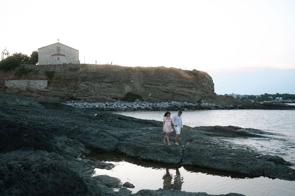 Coastal landscape with rocky cliffs and ocean waves crashing against the shoreline at sunset.