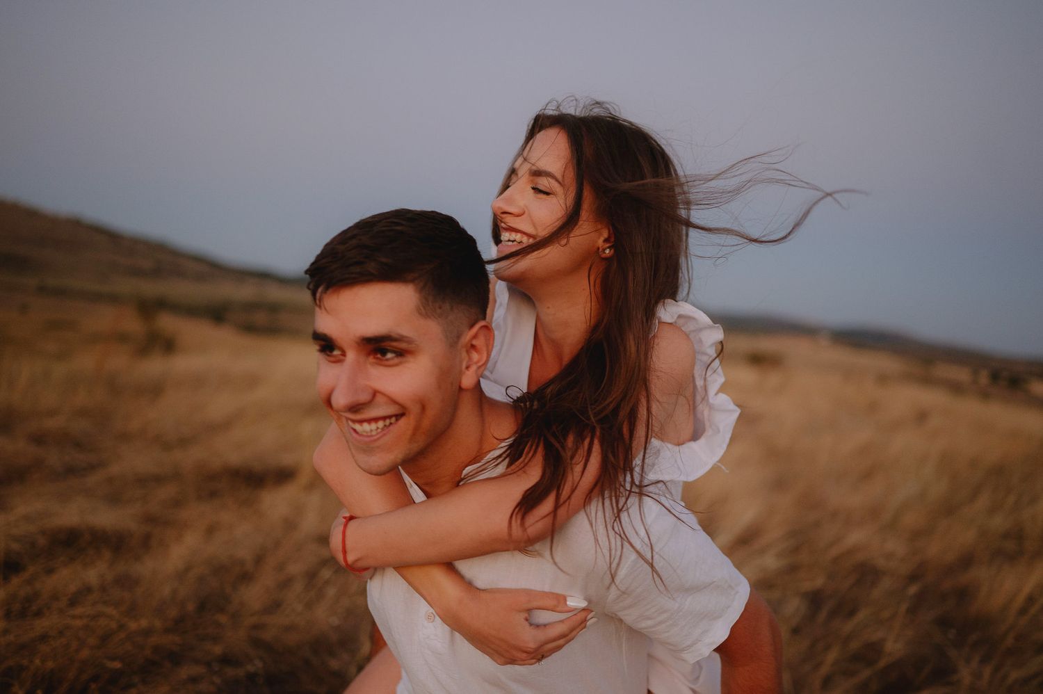 A couple shares joyful moments together in a golden field during sunset.