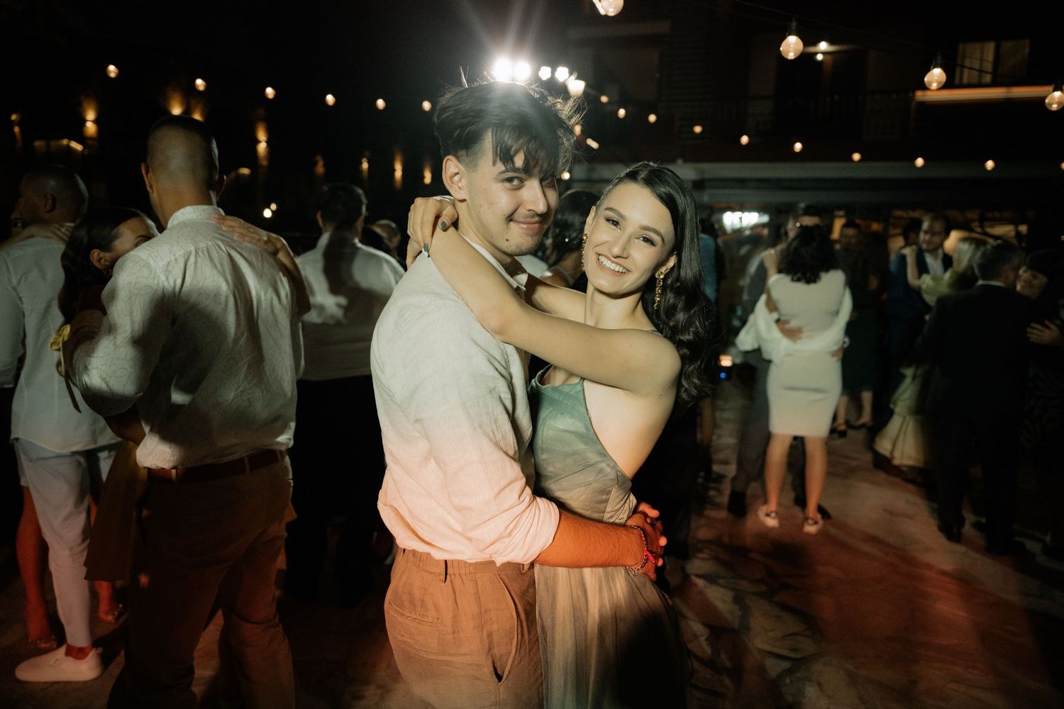 Couples slow dancing together on a dimly lit dance floor at an evening event.
