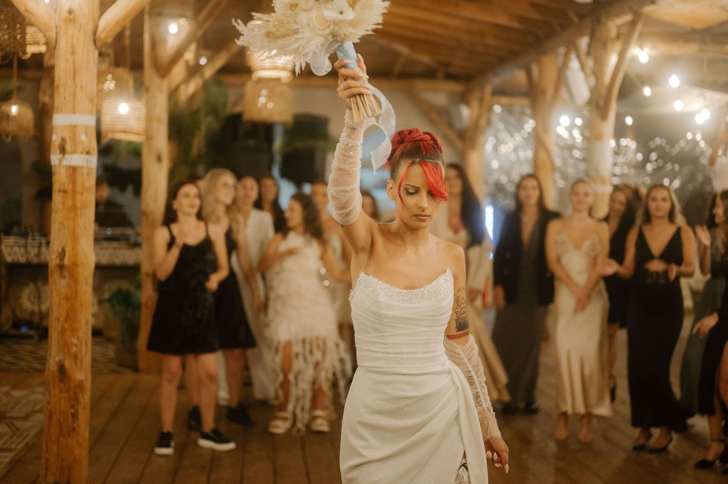 Guests celebrate at a barn wedding reception with twinkling lights creating a warm, festive atmosphere.