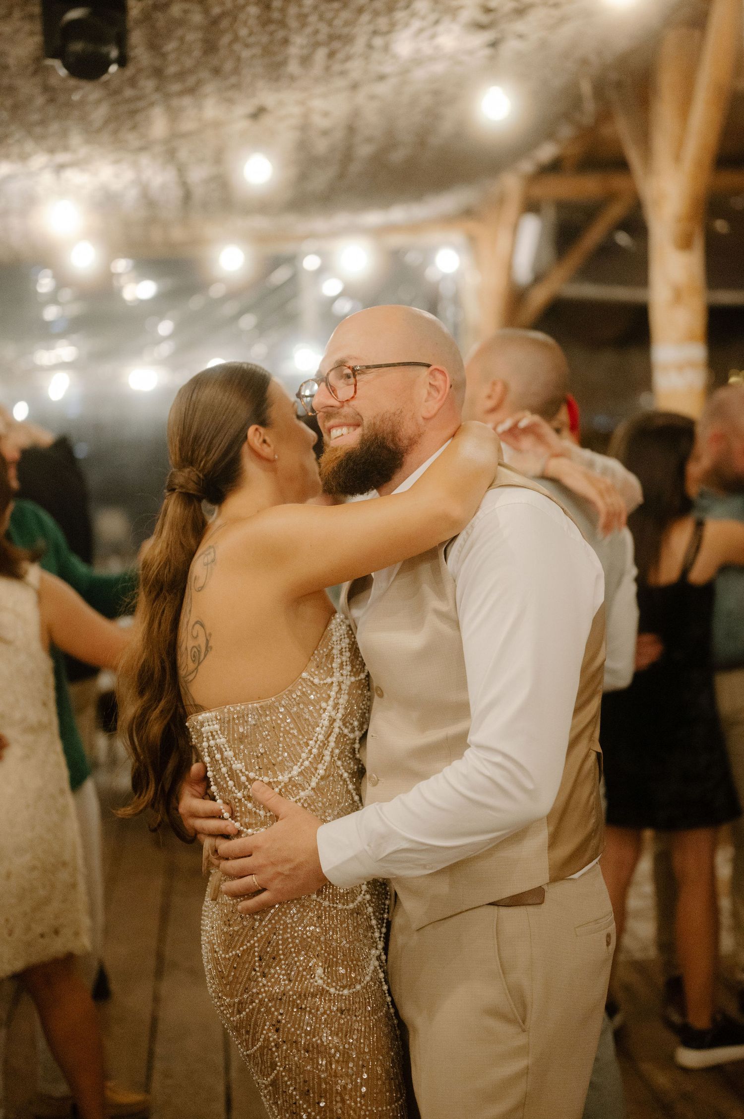 A couple shares a romantic dance moment under twinkling lights at an indoor venue.