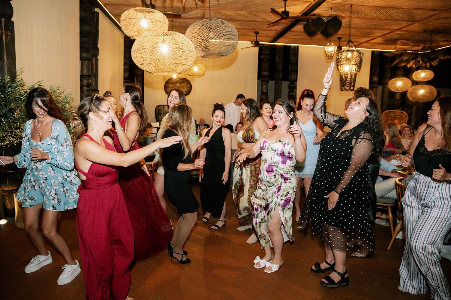 Wedding reception dance party with guests enjoying themselves under warm lighting.