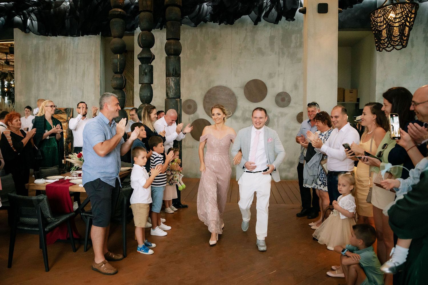 Wedding guests form an aisle and applaud during a celebration.