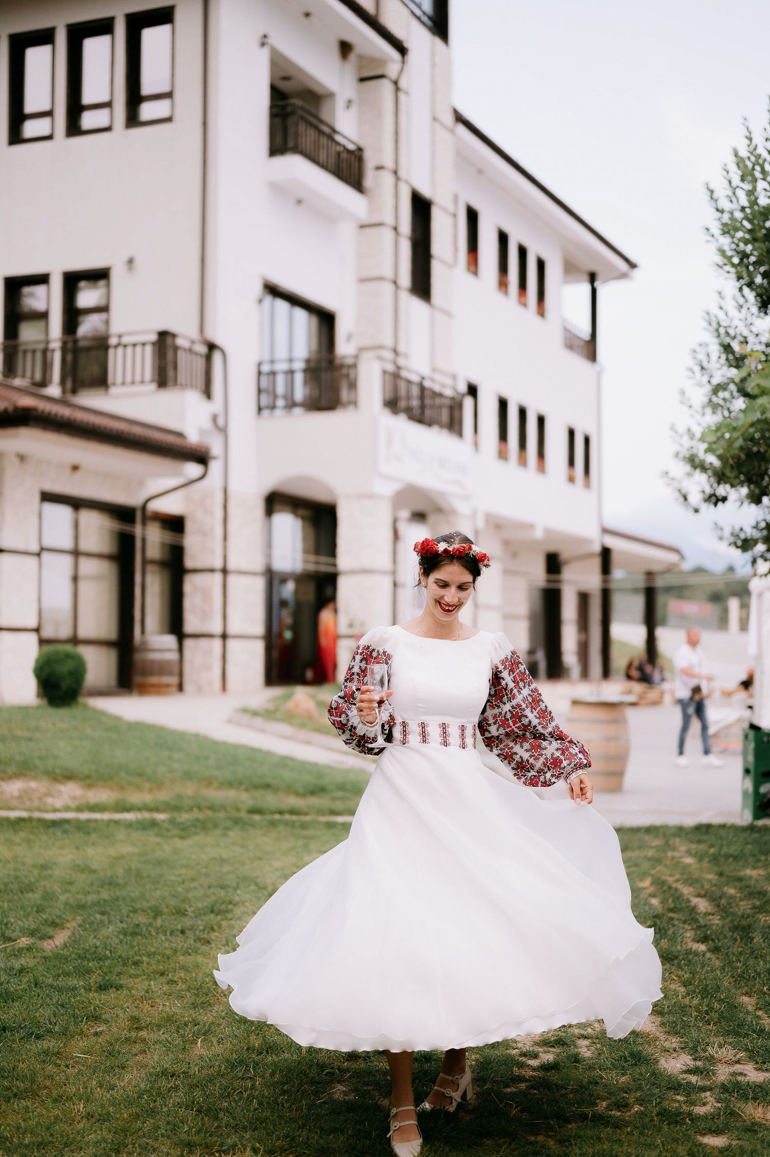 Dancing motion shots in white embroidered dress against architectural background.