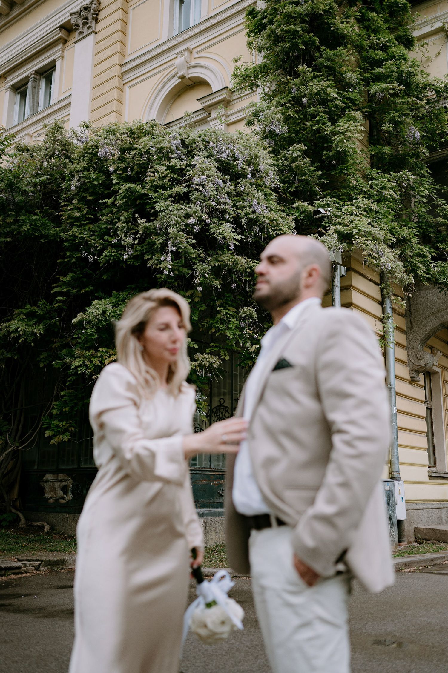 Dancing couple in coordinated beige outfits against classical architecture.