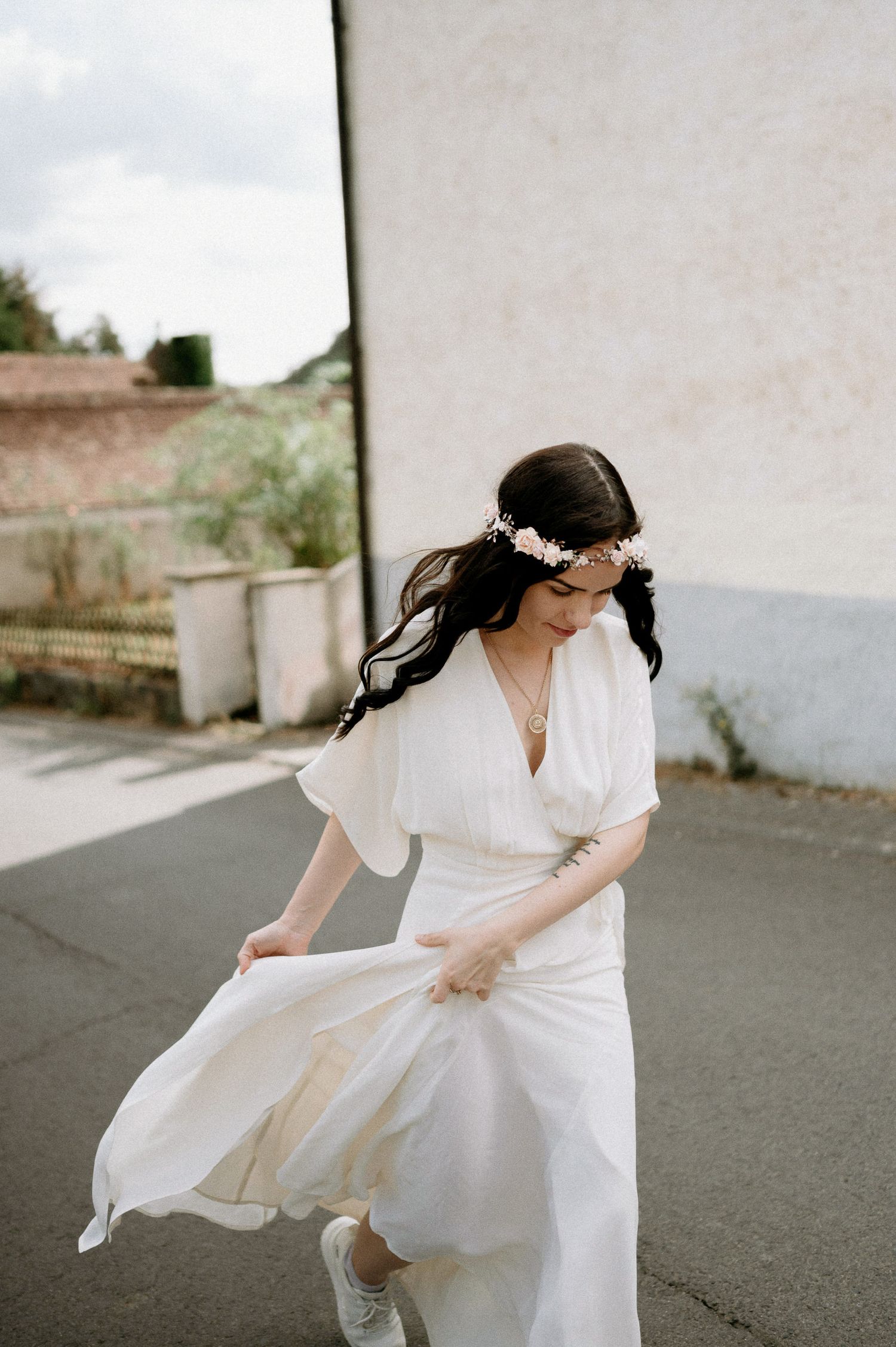 A flowing white wedding dress swirls gracefully on a street in an artistic motion shot.