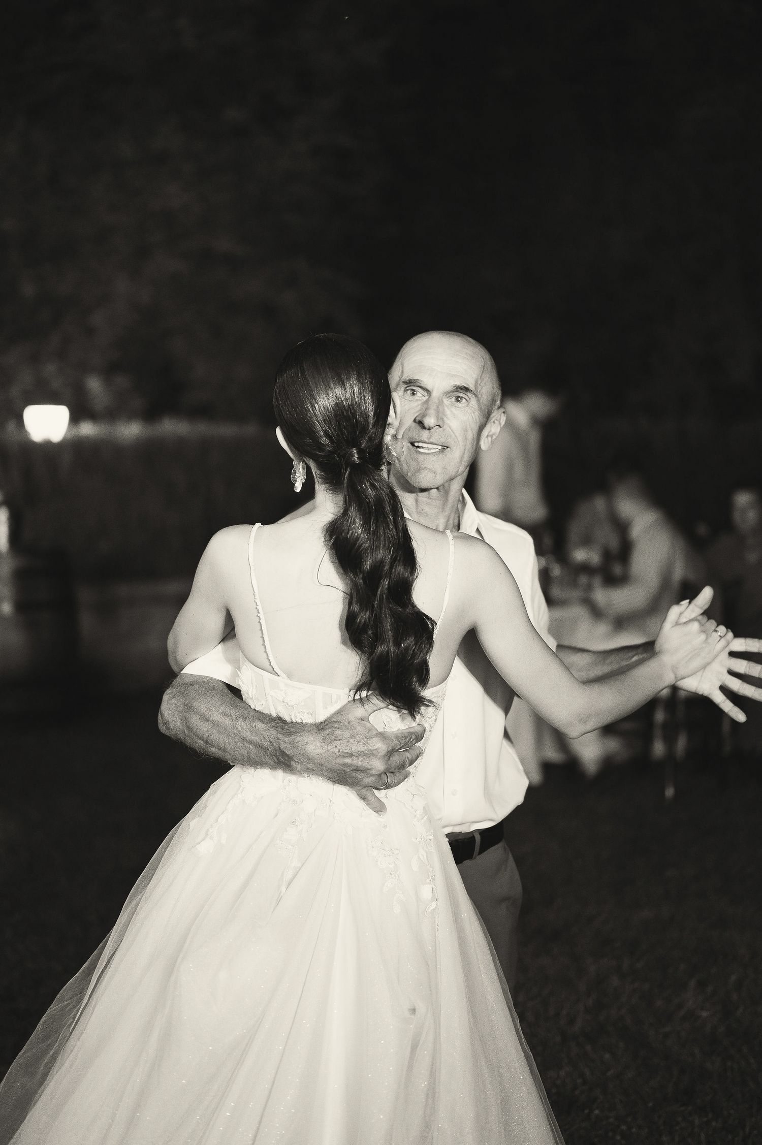 A couple performs a romantic dance together at their outdoor evening wedding reception.
