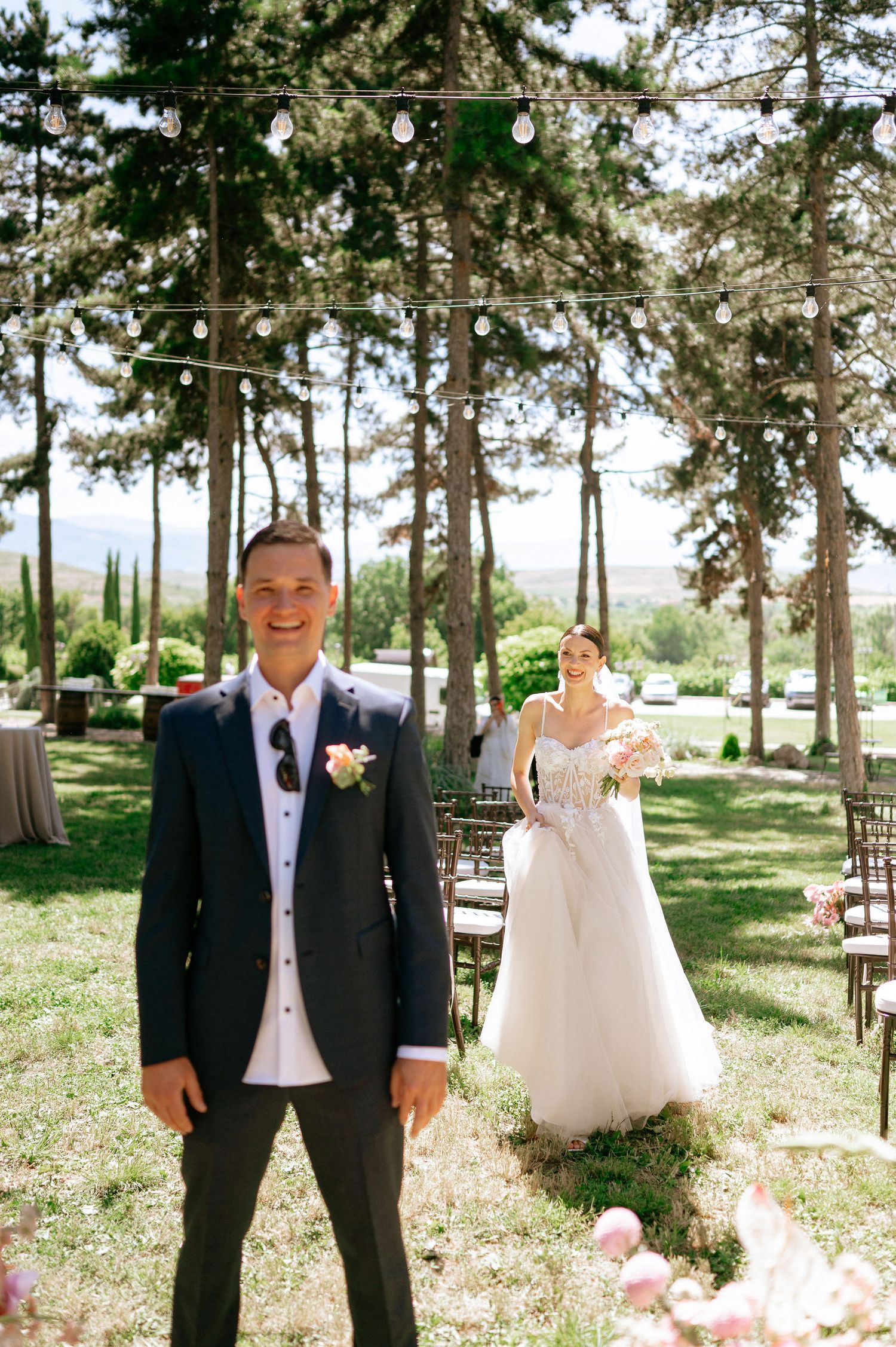 Pine forest wedding ceremony site decorated with pink floral arrangements.