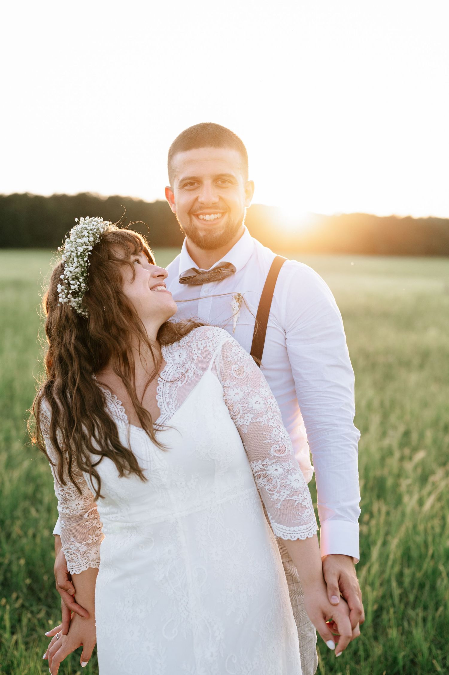 Joyful wedding couple embracing in a sun-drenched field.