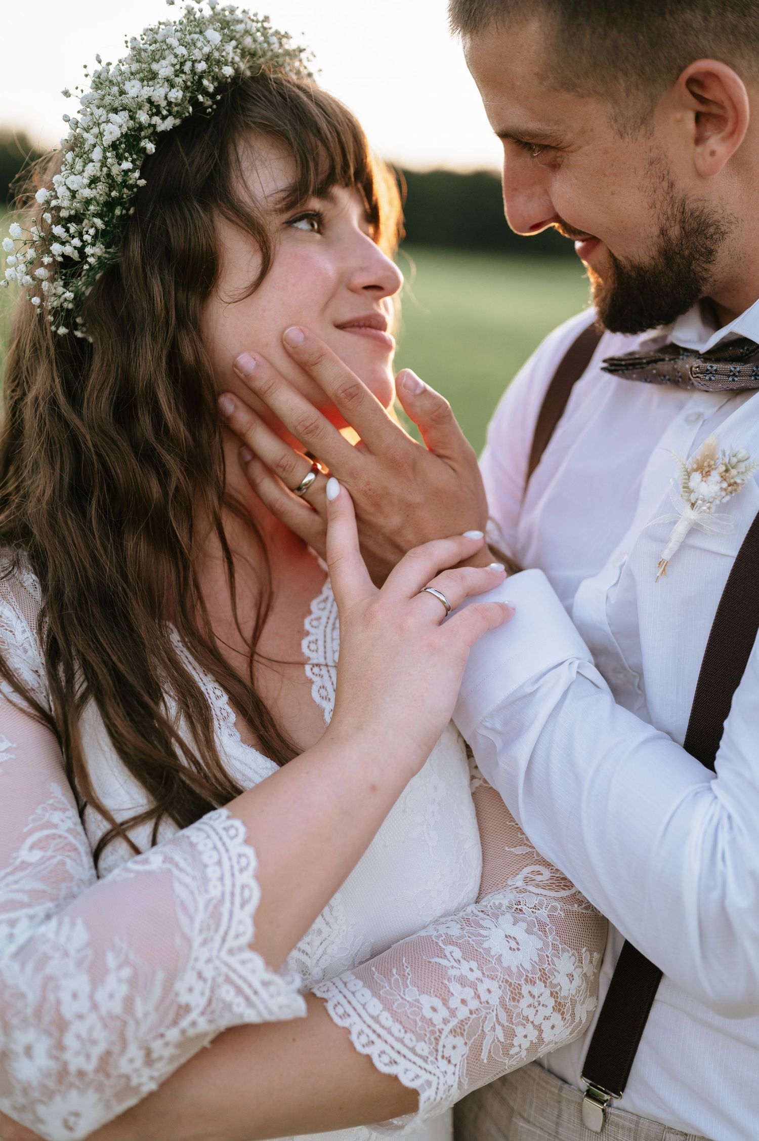 Romantic sunset portrait showing tender moment between newlyweds in outdoor setting.