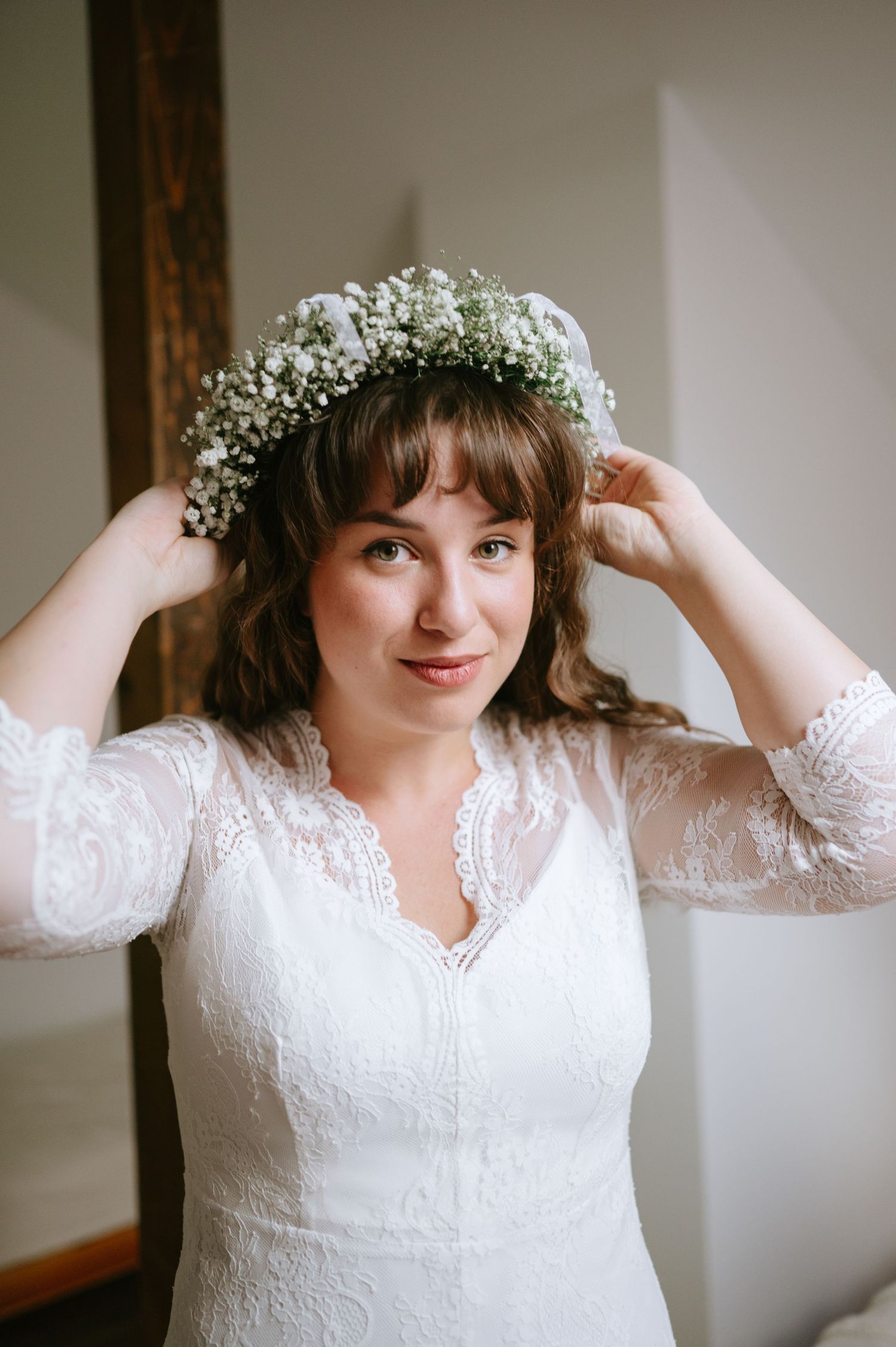 White lace wedding dress with floral crown photographed in natural light.