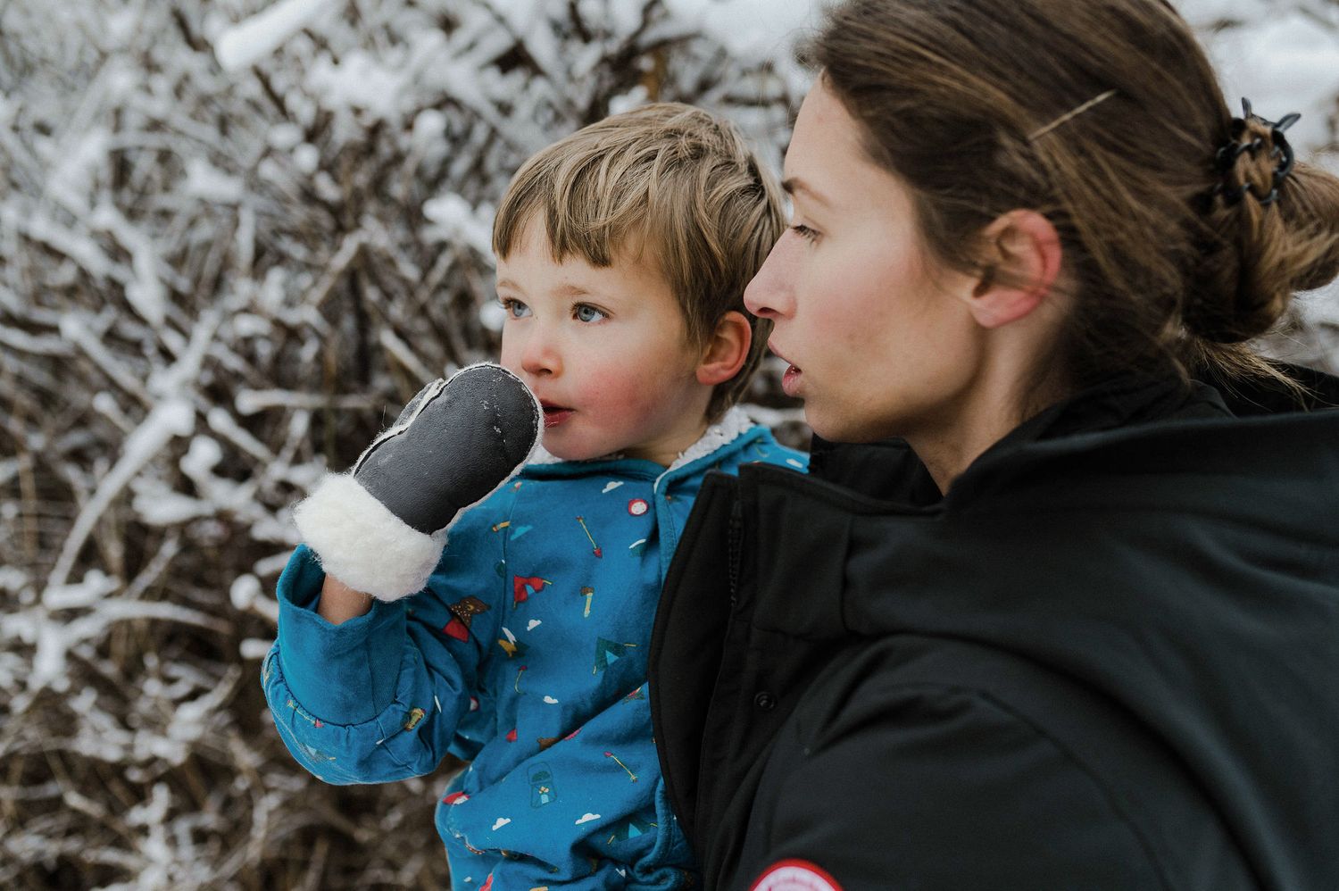 Two people enjoy a winter day outdoors while playing with snow in warm winter clothing.