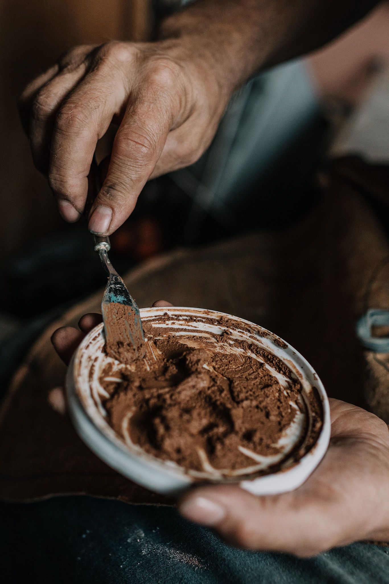 Close-up of hands holding a plate with brown textured material.
