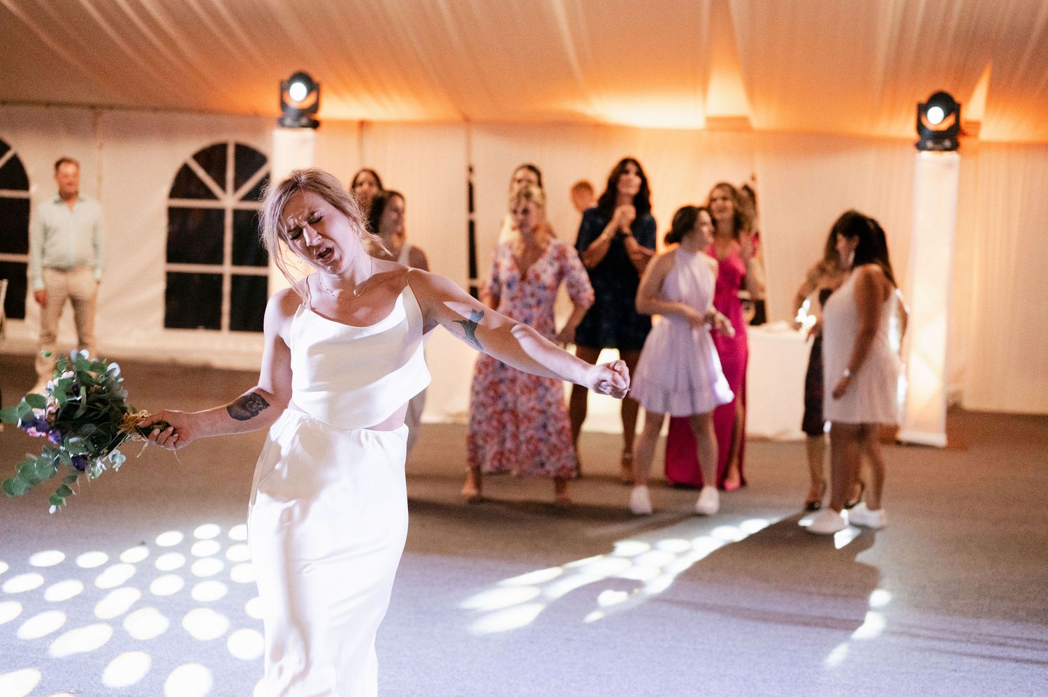 Wedding guests dance and celebrate on an illuminated dance floor during an evening reception.
